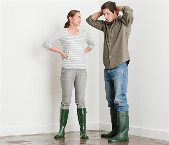 Two people standing on wet flooring in green rain boots 