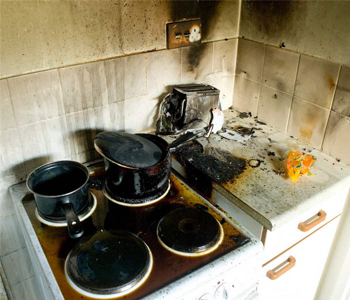 a fire damaged kitchen with soot covering the walls and stove